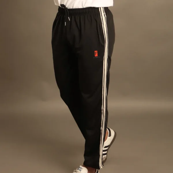 Hombre usando pantalón deportivo negro con franjas laterales beige y logotipo Fit Fornes, ideal para gimnasio y estilo casual.