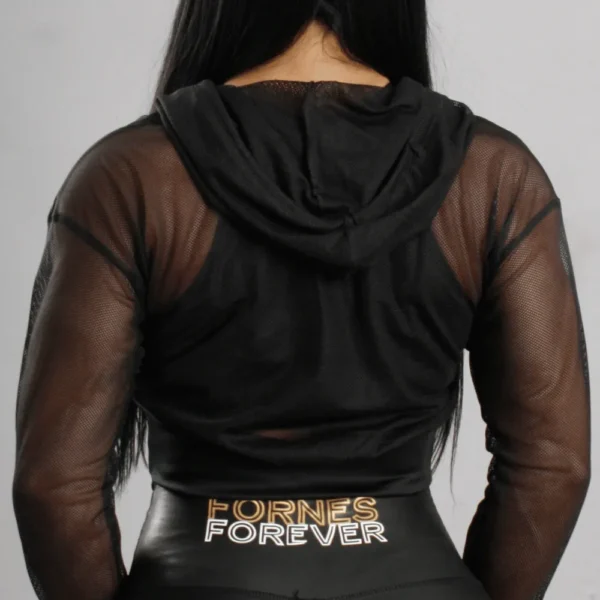 Mujer posando con crop top de malla negra transparente, capucha y mangas largas con logotipo Fit Fornes