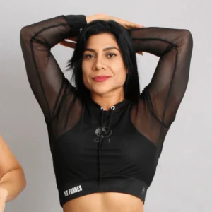Mujer posando con crop top de malla negra transparente, capucha y mangas largas con logotipo Fit Fornes en la cintura.