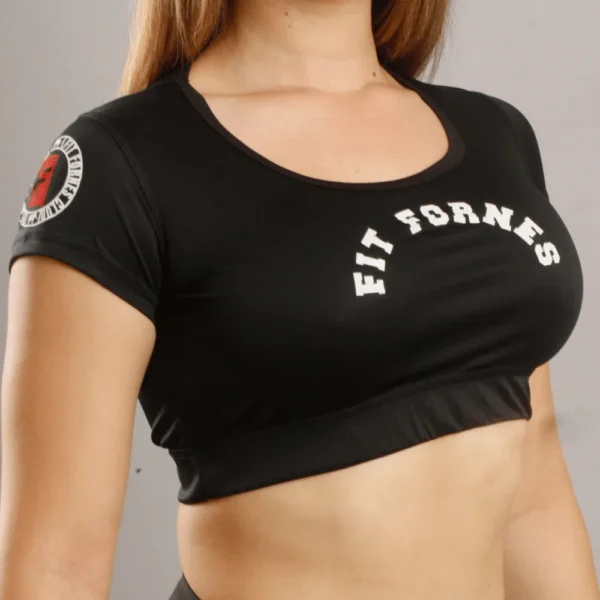 Mujer usando crop top deportivo negro de manga corta con logotipo Fit Fornes en el pecho y parche en la manga.